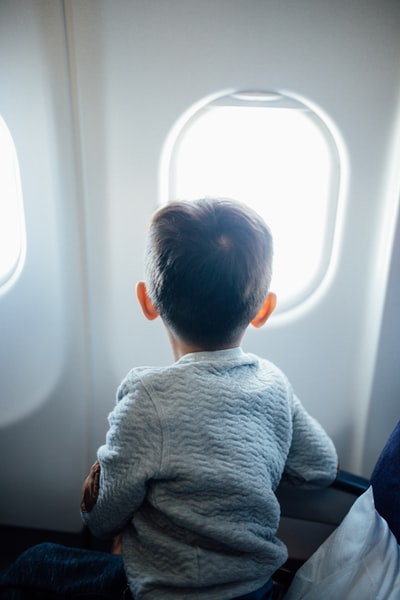 坐在飞机座位上看窗户的男孩